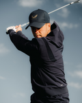 Male golfer wearing Midnight Navy Pinnacle Performance Hoodie mid swing with a cap