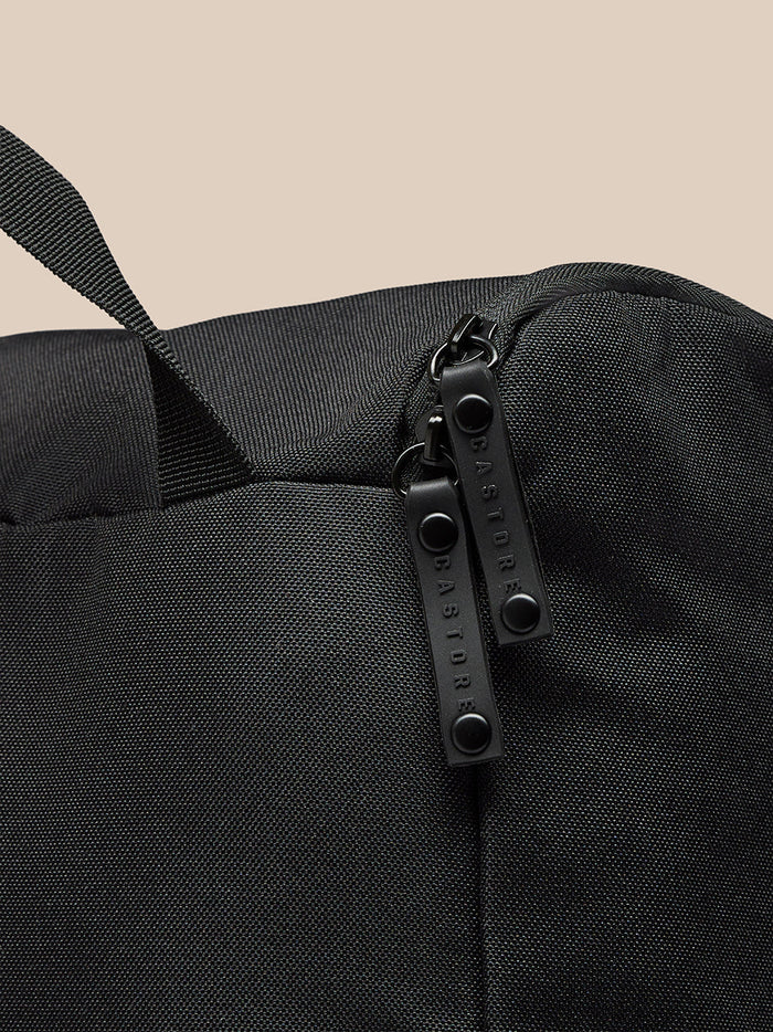 Close-up of black boot bag showing textured fabric and two zipper pulls with Castore branding