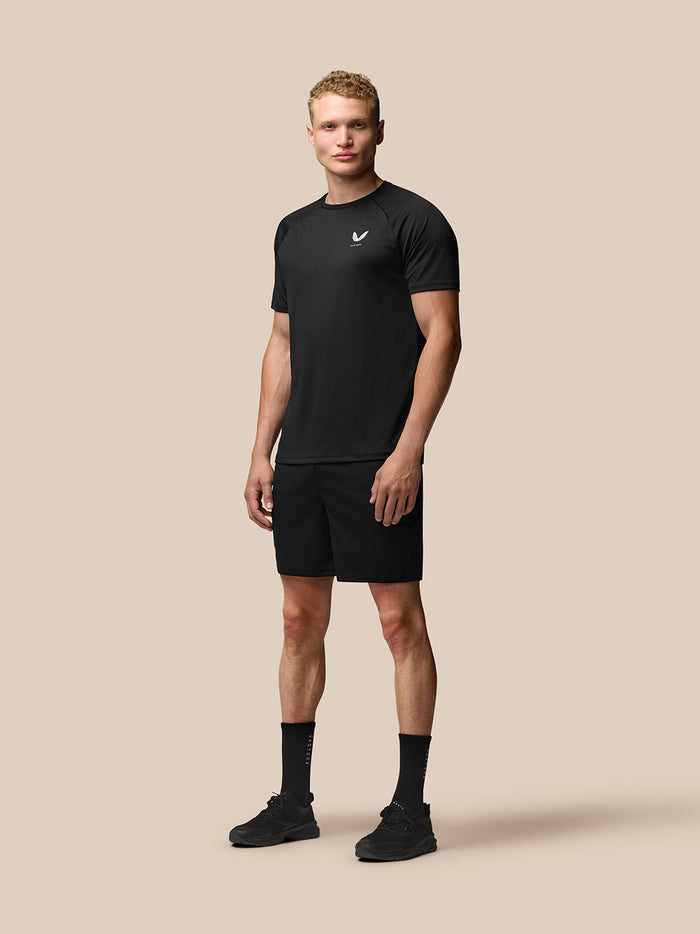 Full body portrait of a male model wearing black Adapt Training shorts with a matching black top for an athletic look.