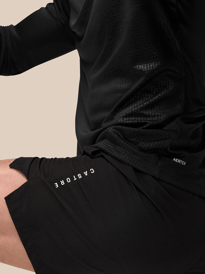 Close-up side view of Adapt Training 6in shorts in black showing Castore branding on the left thigh and Aertek label at the rear