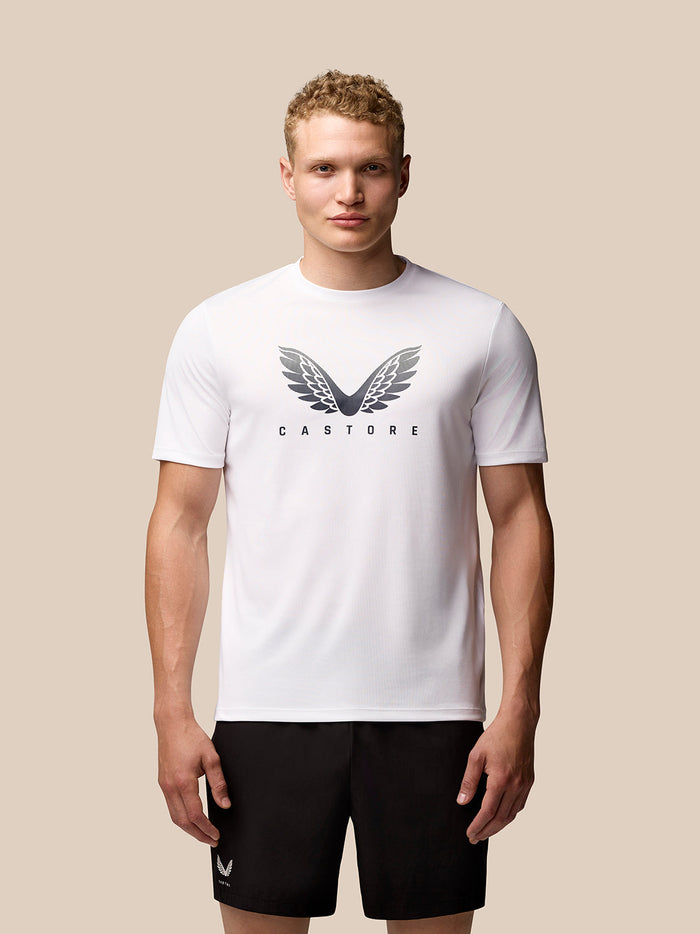 Male model wearing white Adapt Training T Shirt with Castore wings logo on chest against a beige background