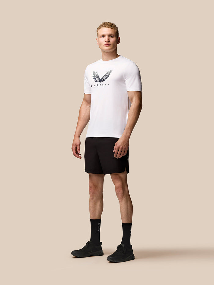 Male model wearing white Adapt Training T-Shirt with Castore wing logo on chest and black shorts.