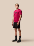 Male model wearing pink Adapt Training T Shirt with Castore wings graphic on chest and black shorts.