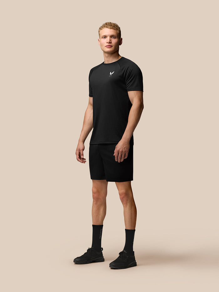 Male model wearing black Adapt Training T-Shirt with crew neck and raglan sleeves; Castore logo on left chest.
