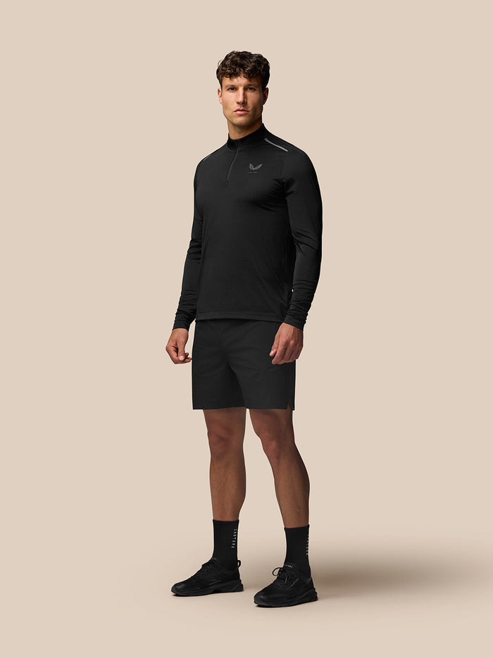 Full-body shot of a man in a black Apex Training Quarter Zip Top with stand collar.