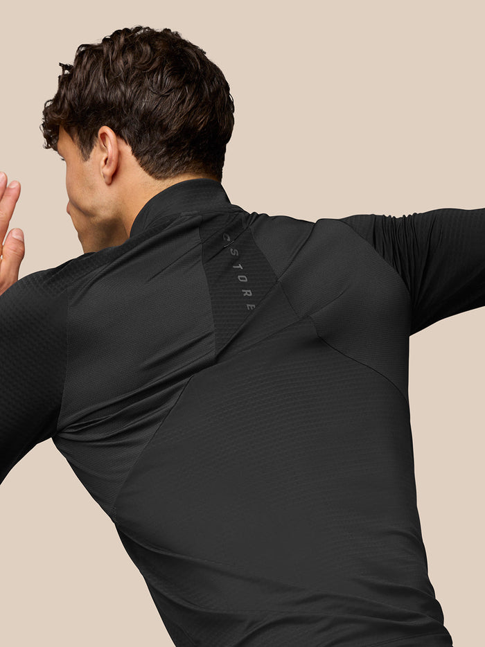 Back view of a man wearing a black Apex Training Quarter Zip Top with Aeromesh panels.