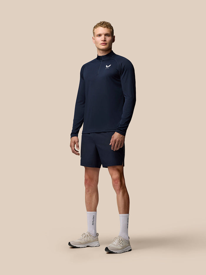 Male model wearing midnight navy Adapt Training Quarter Zip Top with stand collar center front zip and chest logo