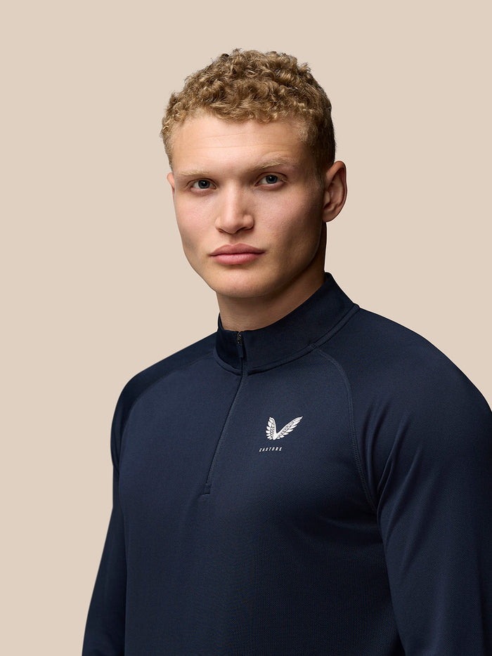 Front view of navy Adapt Quarter Zip Top showing white Castore branding on left chest
