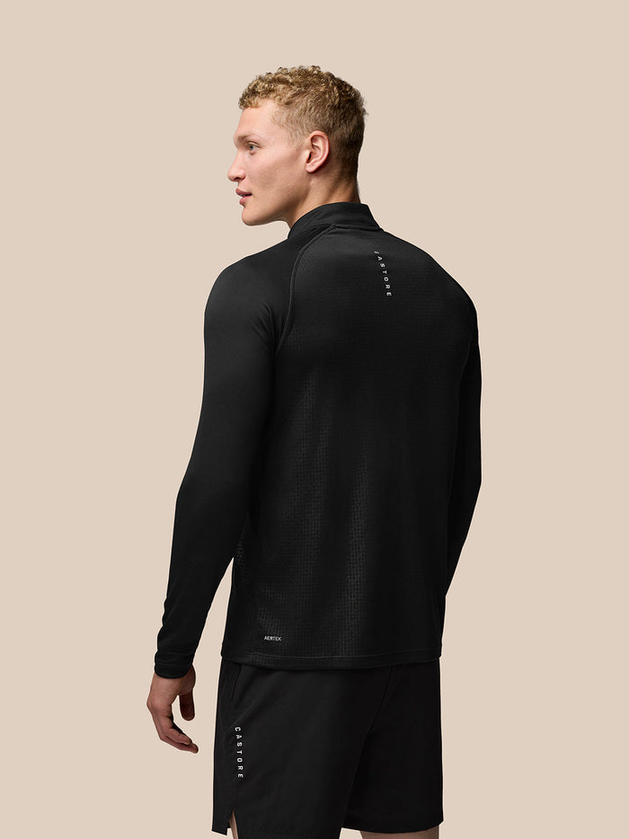 Back view of male model wearing black Adapt Print Quarter Zip Top with geometric texture and branding on upper back.