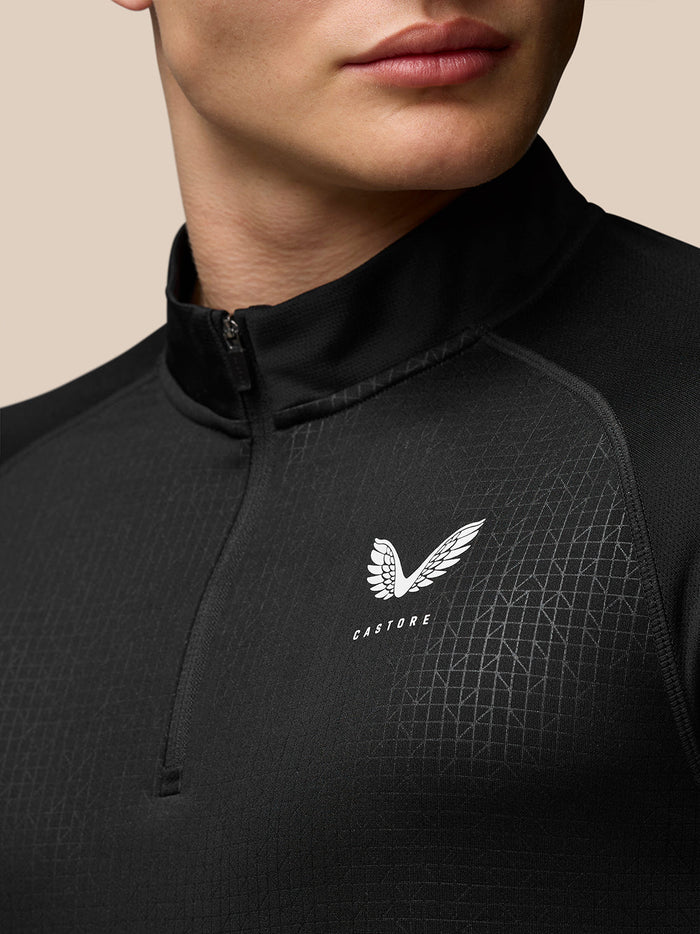 Close-up of black Mens Adapt Print Quarter Zip Top with stand collar and front zip, geometric pattern, Castore branding on left chest and upper back, and Aertek branding at lower back