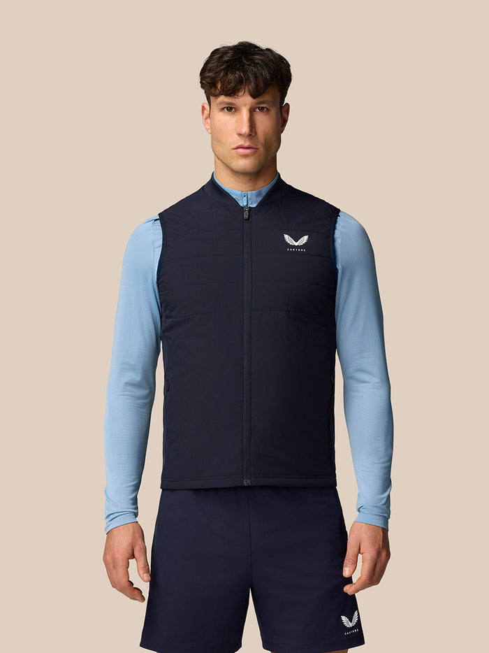 Front view of a man wearing navy Apex Training Gilet over a light blue top.