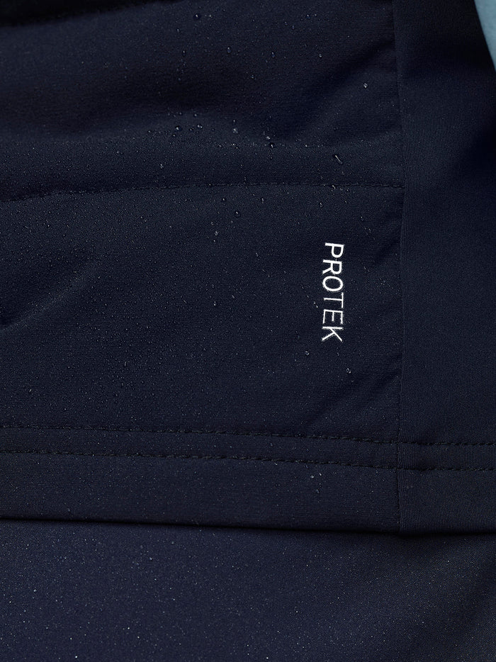 Man wearing navy Apex Training Gilet with Castore and ProTek branding, holding a navy bag