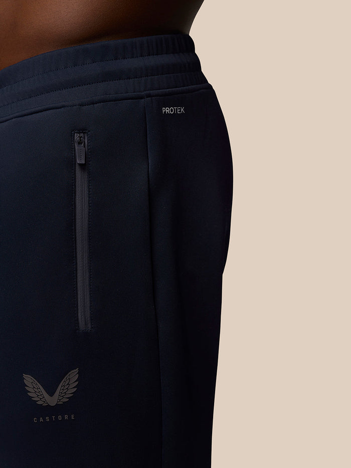 Close up of navy joggers with Protek branding at the waist and a side zip pocket, Castore logo visible on the leg
