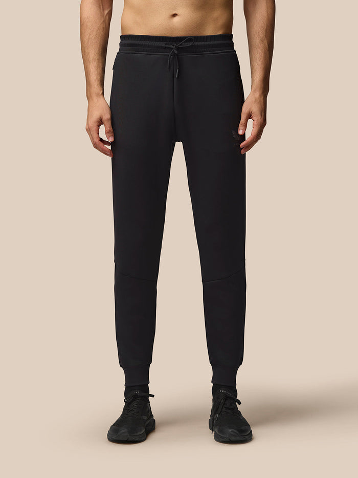 Model wearing black Flex Lifestyle Joggers with elastic drawcord waistband and cuffed ankles; logo on left thigh.