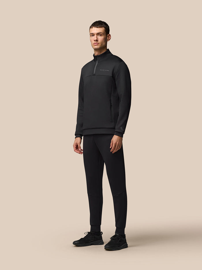 Male model wearing a black Flex Lifestyle Joggers outfit with a matching top, standing in a studio.