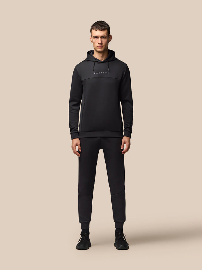 Full-body view of a male model in black Flex Hoodie and matching joggers with CASTORE branding on the chest