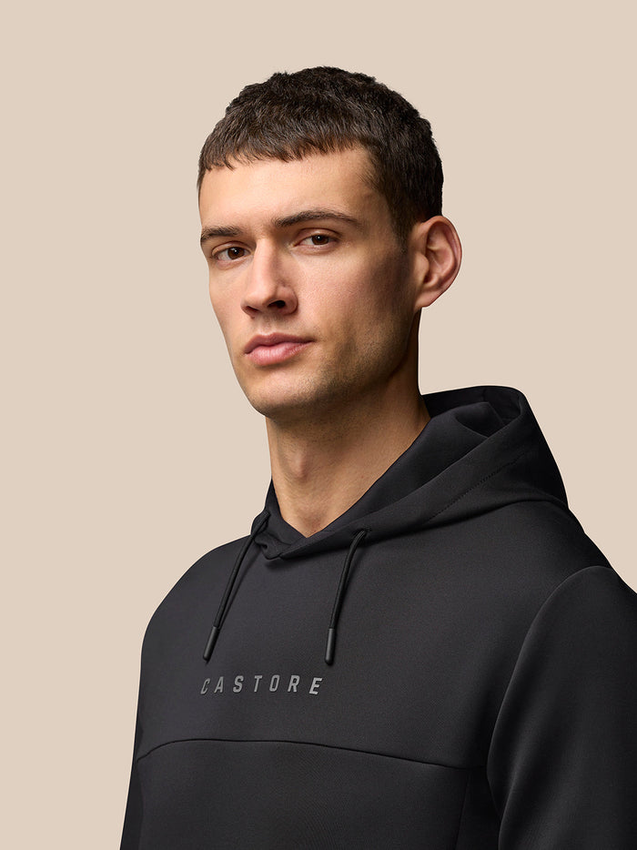 Portrait of a model wearing black Flex Hoodie with hood up and CASTORE logo on the chest