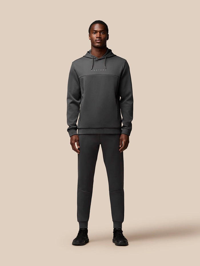 Full-length front view of a man in the Charcoal Flex Lifestyle Hoodie with joggers; Castore logo on chest and Protek branding at the lower left back.