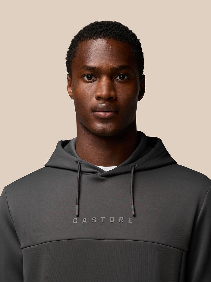 Close-up of the charcoal hoodie chest area showing CASTORE logo and hood drawstrings.