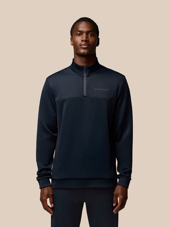 Male model wearing navy Flex Quarter Zip top with zip pockets and Castore branding on the chest