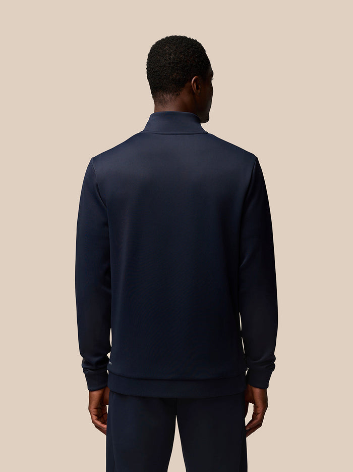Rear view of a model wearing navy Flex Quarter Zip top highlighting the high collar and clean lines
