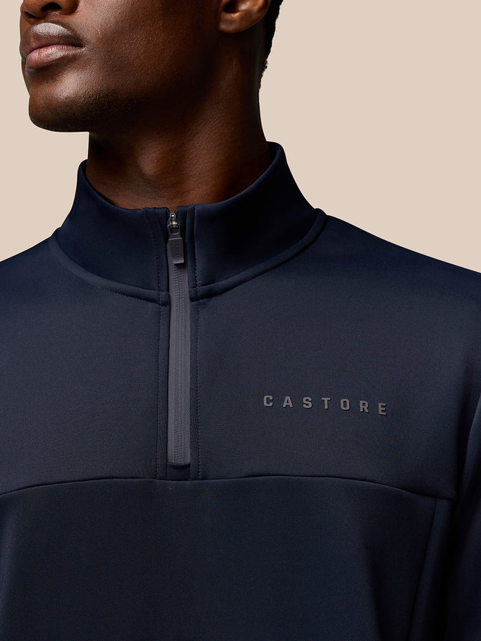 Close-up of navy Castore Flex Quarter Zip top showing front zipper and Castore logo on left chest