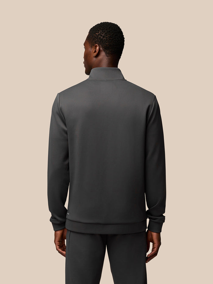 Back view of a man wearing a charcoal Flex Lifestyle 1/4 Zip top with a clean silhouette and ribbed hem.