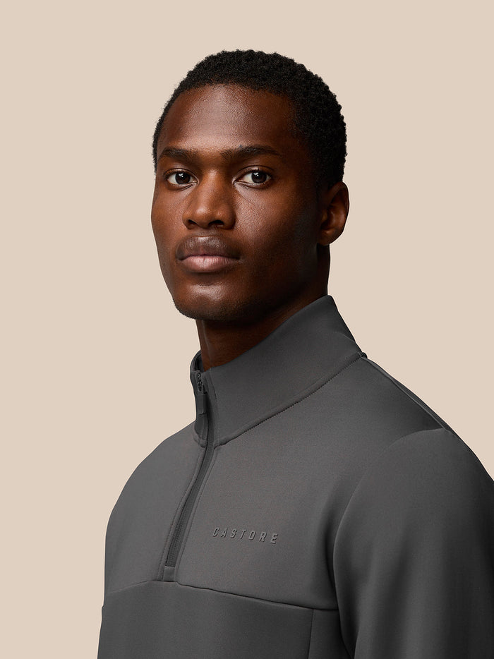 Close up side profile of a man in a charcoal Flex Lifestyle 1/4 Zip top with high collar and Castore branding on the chest.