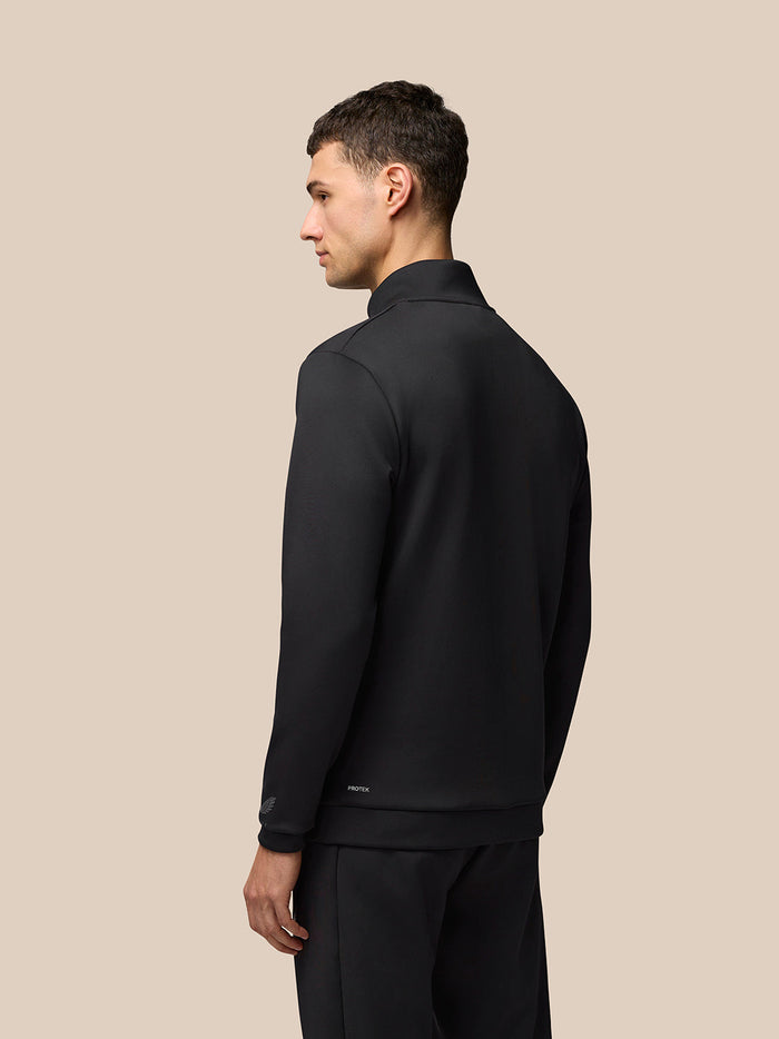 Back view of a man in the black Castore Flex Lifestyle 1/4 Zip top with a plain back panel and Protek branding at the hem.