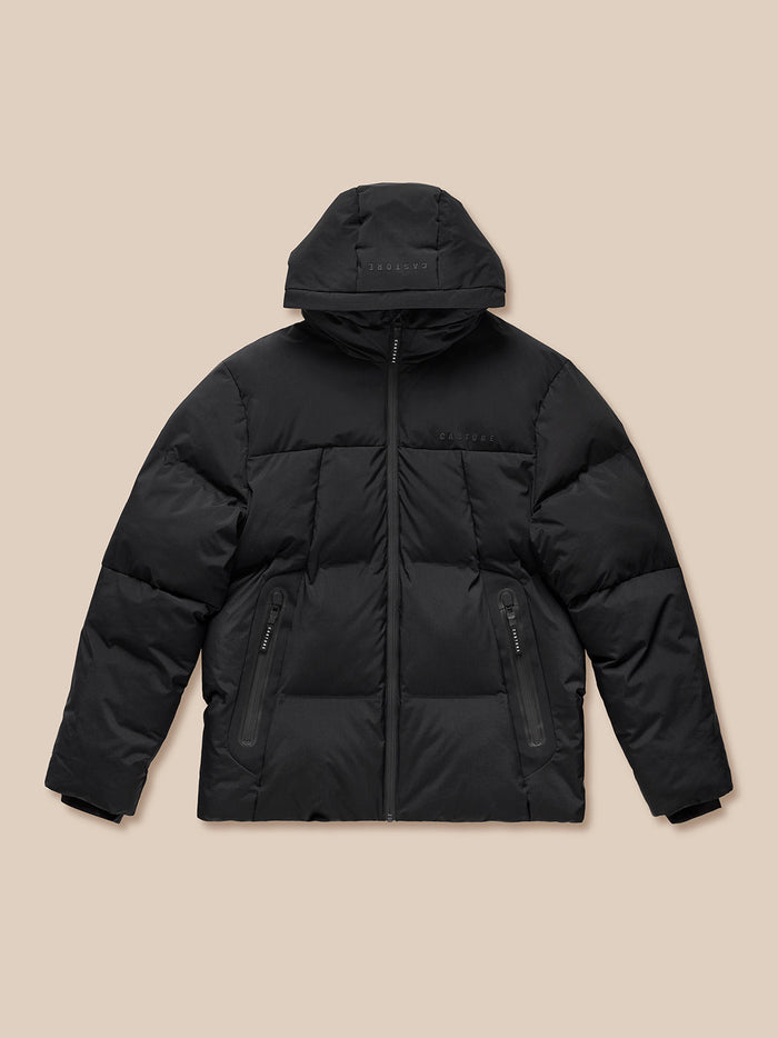 Front view of a black puffer jacket laid flat showing full zip and zipped pockets with Castore branding on chest
