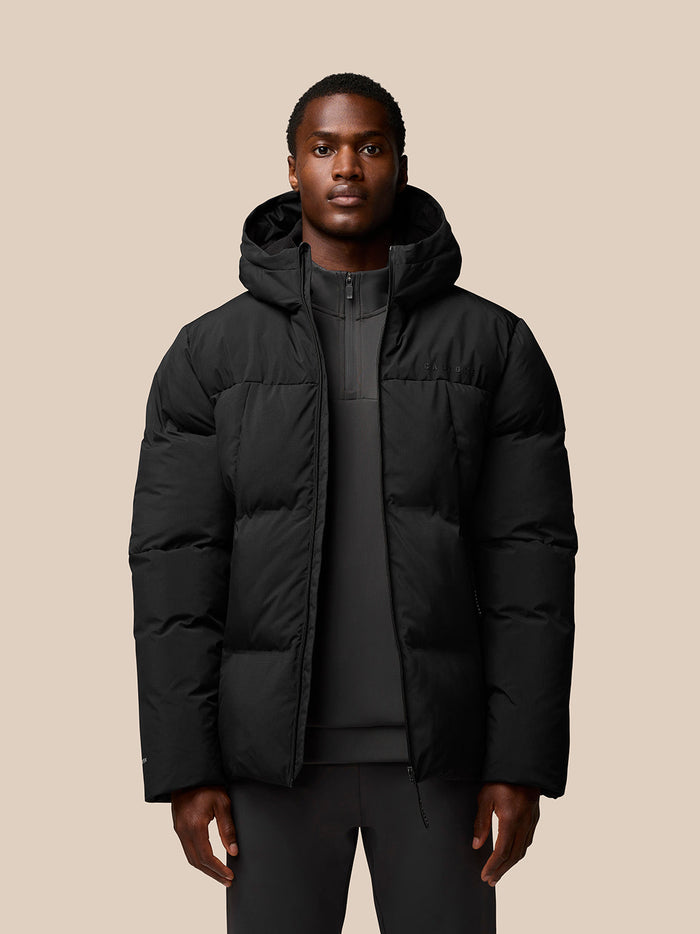 Man wearing black hooded puffer jacket with front zip and quilted panels
