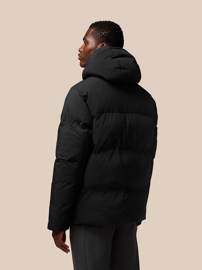 Back view of a man wearing a black puffer jacket with a large hood
