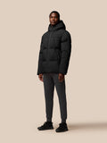 Full body shot of a man in a black hooded puffer jacket with zip pockets and Castore branding on the chest