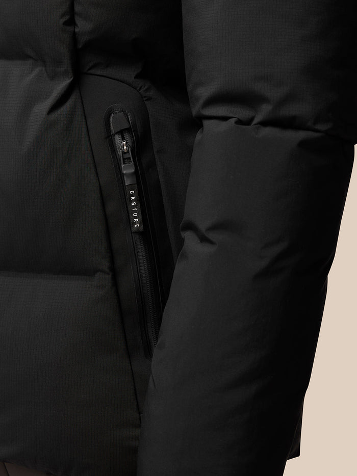 Close up of a black puffer jacket vertical side pocket zip with Castore branded zipper pull