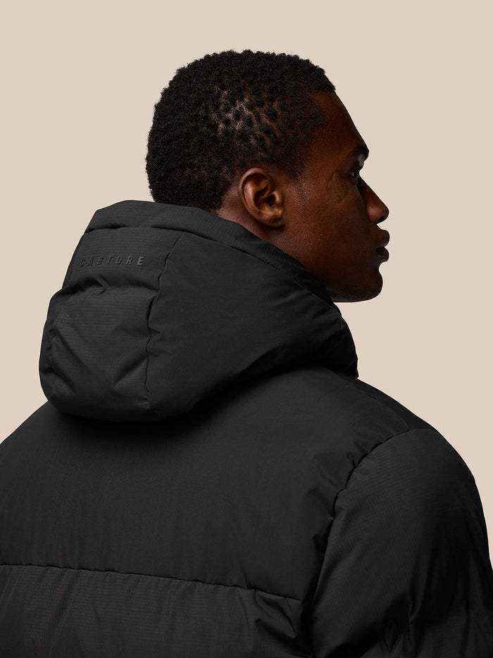 Back view of a black hooded puffer jacket with Castore branding on the hood
