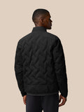 Back view of a man wearing a black padded jacket with chevron quilting and a stand collar.