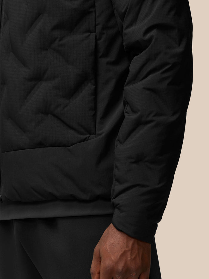 Close-up of black padded jacket fabric showing subtle texture and side seam.