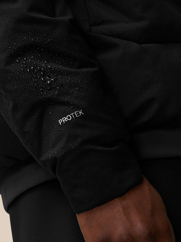 Close-up of black padded jacket sleeve with Protek branding and water droplets