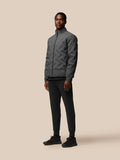 Model wearing charcoal Quilts Lifestyle Jacket with stand collar and front zip, beige backdrop