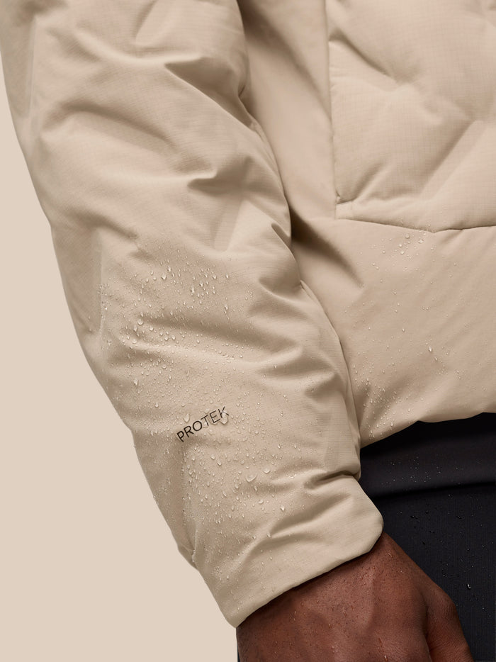 Close up of a mushroom colored padded jacket sleeve with water droplets and ProTek branding visible