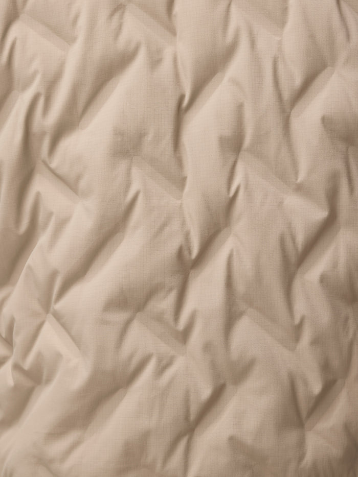 Close-up of mushroom beige fabric with a fine grid texture for the padded jacket