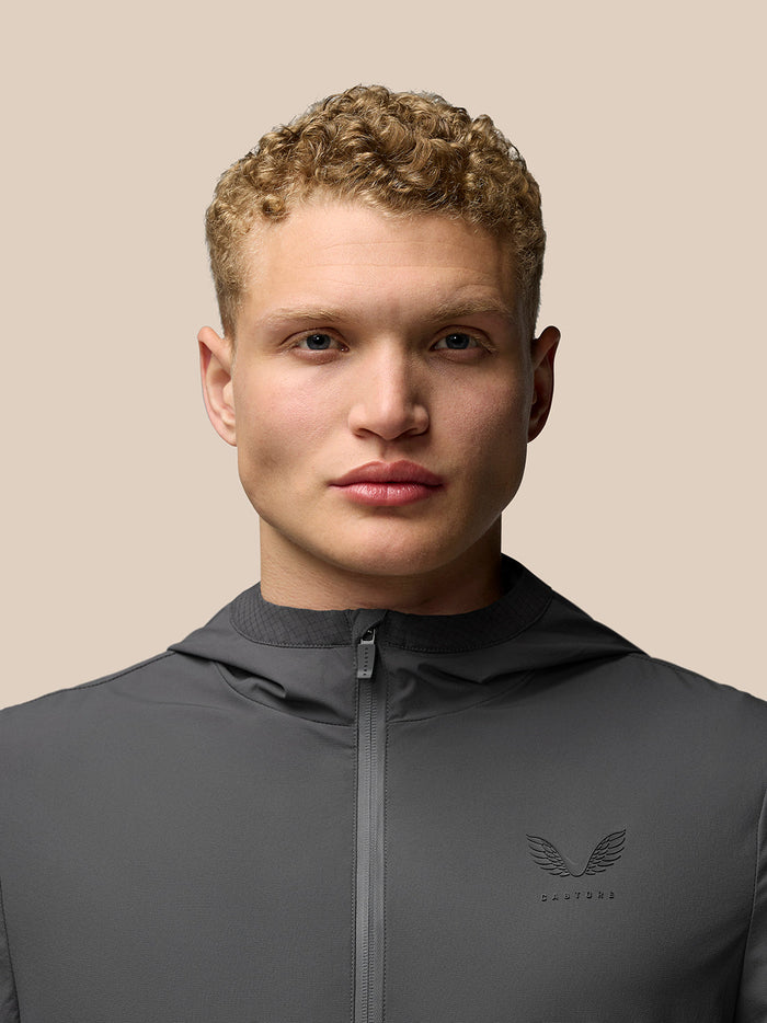 Close-up of male model wearing charcoal Flex Jacket with hood and chest logo