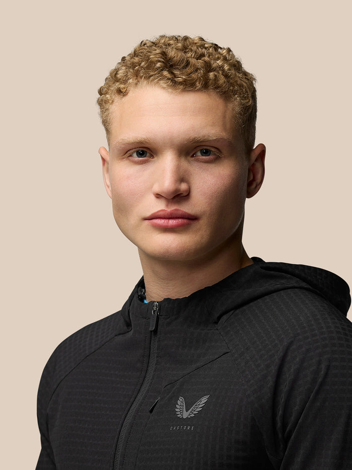 Close-up of a model wearing the black Flex Winterised Jacket with front zip and Castore logo on the chest
