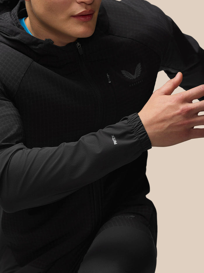 Full-length view of a male model wearing the black Flex Winterised Jacket with hood and blue top underneath