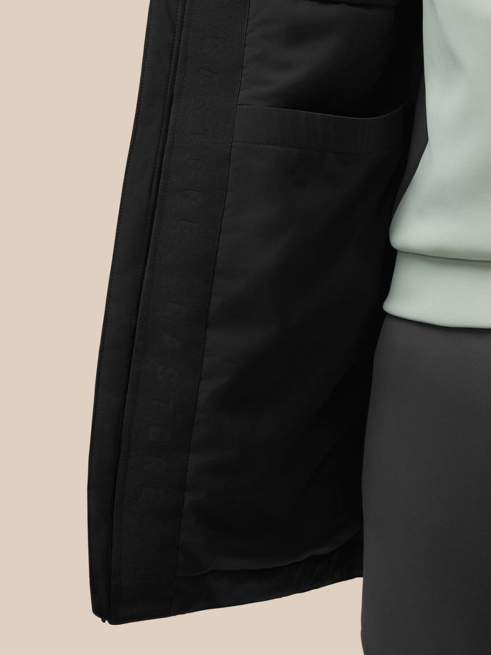 Close-up side view of a black longline jacket showing an external pocket and visible inner lining