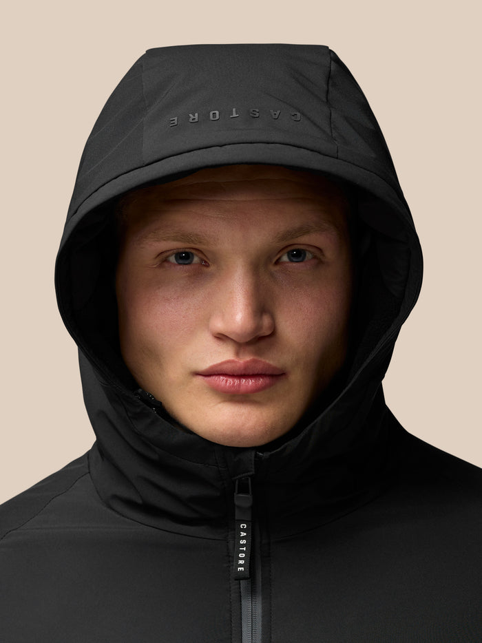 Close-up of a black hooded jacket showing a center front zipper and a hood with inner thermal fabric