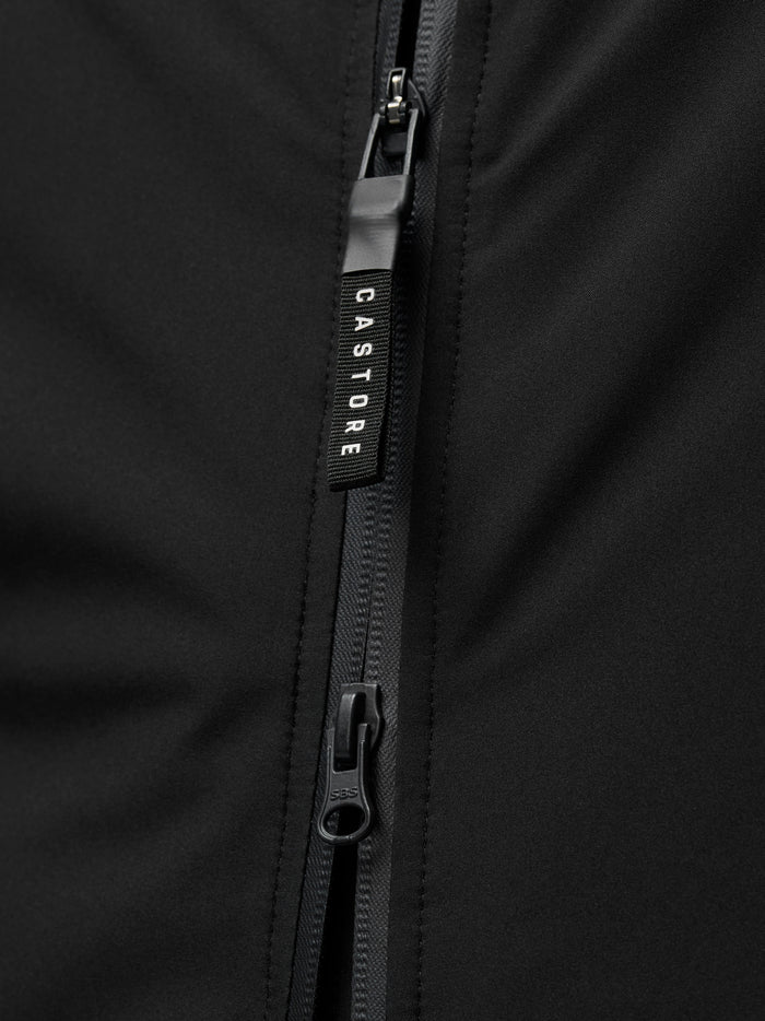 Close-up of a black Castore jacket zipper with branded pull tab against smooth fabric