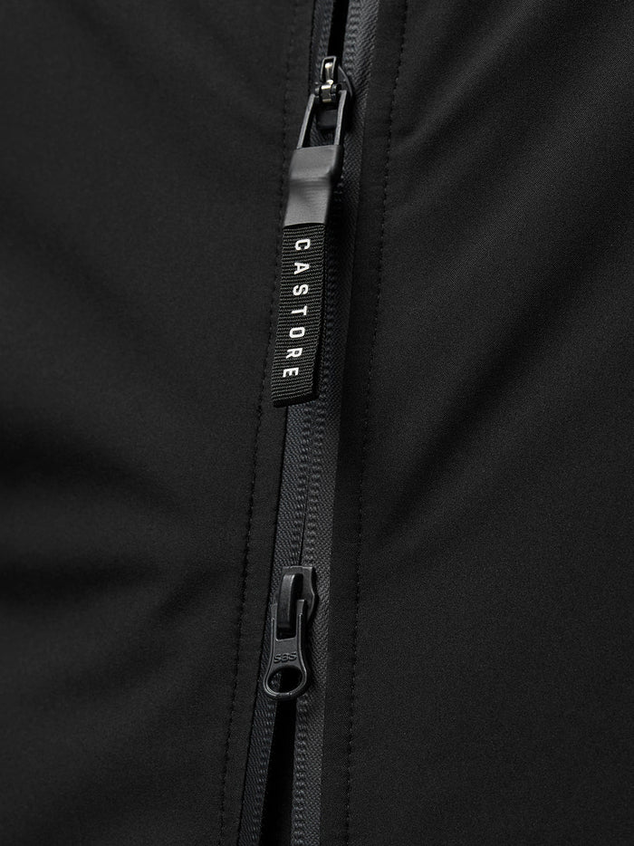 Close-up of the front zip on a black longline jacket with a Castore branded pull tab