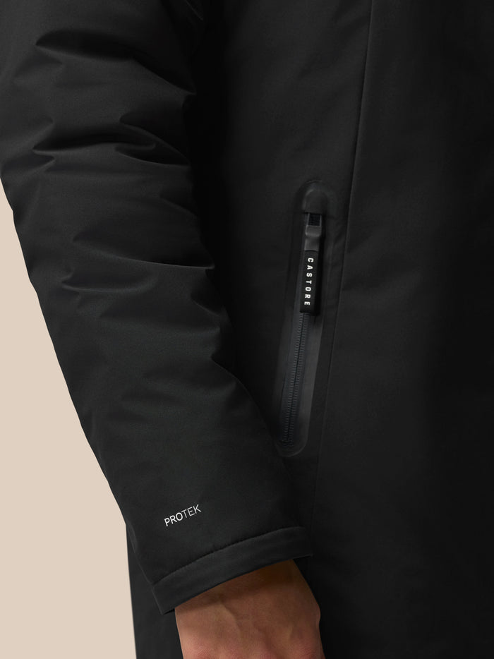 Close-up of black longline jacket sleeve showing a vertical zipper with CASTORE pull and PROTEK branding on the cuff