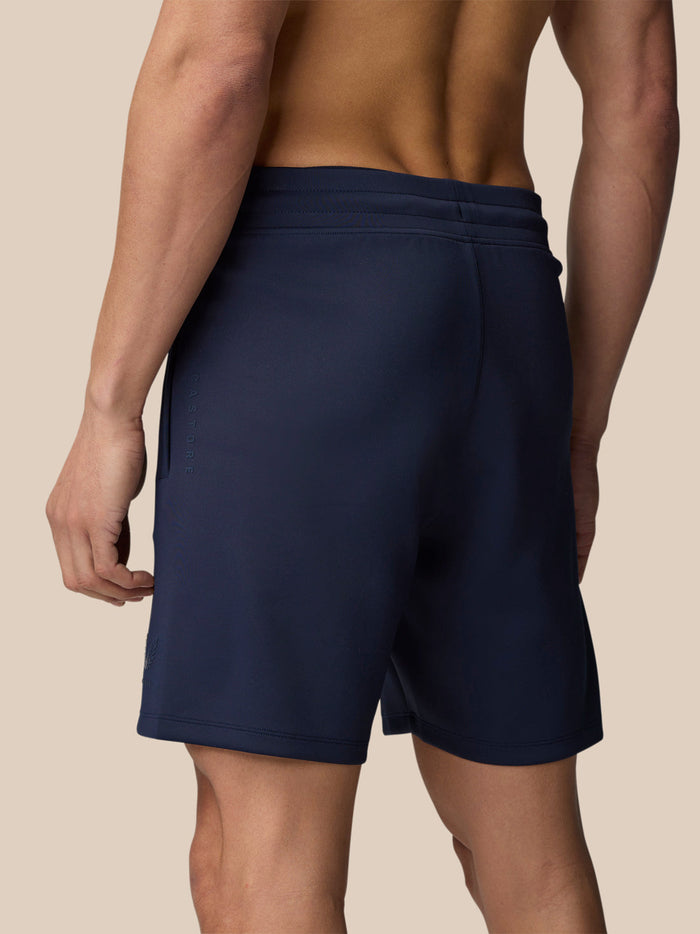 Back view of navy Flex Shorts showing an elastic waistband with drawcord and a subtle leg logo